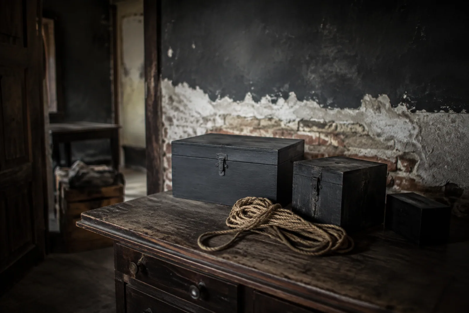 Locked wooden boxes and coiled rope on a desk in an escape-room set.